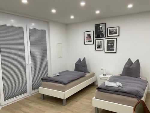 two beds in a bedroom with white walls at Deluxe Apartments Messe Flughafen in Leinfelden-Echterdingen