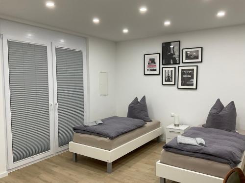 two beds in a bedroom with white walls at Deluxe Apartments Messe Flughafen in Leinfelden-Echterdingen
