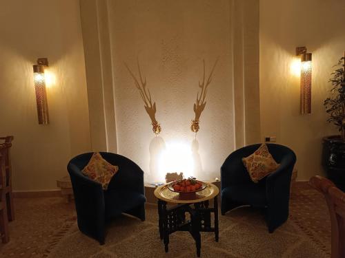 two chairs and a table in a room with a fire at Riad Beni Sidel in Marrakech