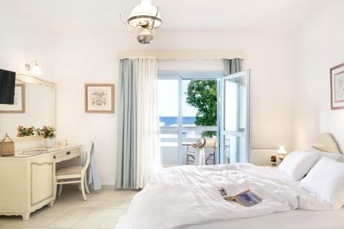 a white bedroom with a bed and a desk and a window at Perigiali in Skiros