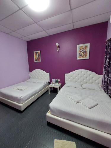 Taman Negara River View Lodge في كوالا تاهان: سريرين في غرفة ذات جدار أرجواني