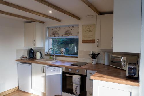 uma cozinha com armários brancos e uma bancada em Rose Hideaway - Forest of Dean Cosy Cabin Retreat em Yorkley