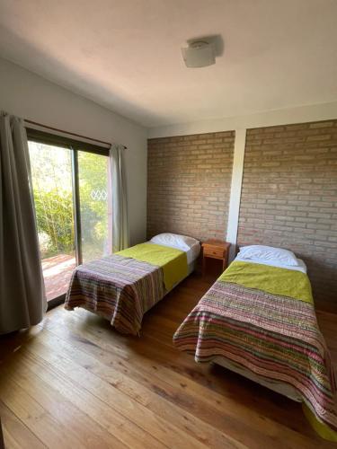 two beds in a room with a window at Casas Pura Vida in Villa General Belgrano