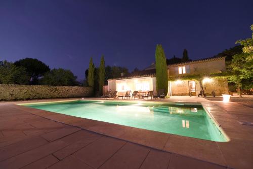 une piscine devant une maison la nuit dans l'établissement Mas du PERUSSIER, à Cucuron