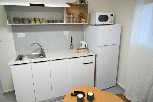 a small kitchen with a white refrigerator and a table at פסגת הדרור in Shelomi