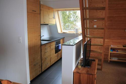 a kitchen with wooden cabinets and a television in it at Haus Gimpel Flumserberg in Flumserberg
