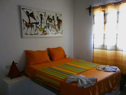 1 dormitorio con 1 cama con una manta colorida en La CASETTA A ZANZIBAR B&B, en Uroa