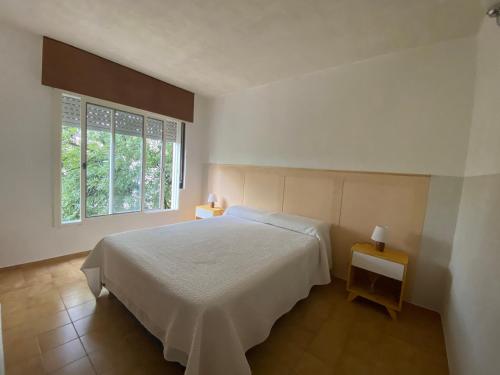 1 dormitorio con cama blanca y ventana en Malvinas Carlos Paz en Villa Carlos Paz