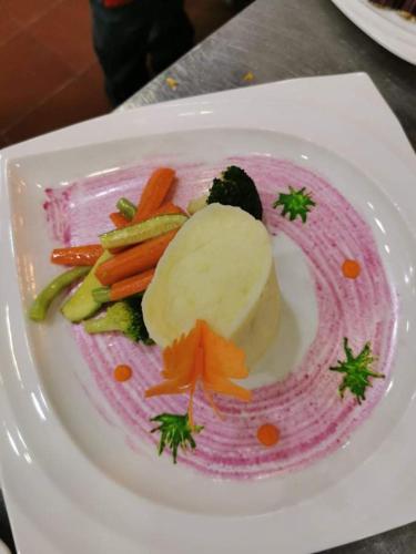 a plate of food with vegetables on a table at Lolia Hotel فندق لوليا الفندقية in Raʼs Tannūrah