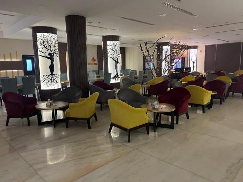 a restaurant with yellow chairs and tables and chairs at Lolia Hotel in Raḩīmah