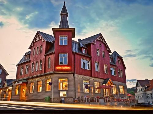 un gran edificio rojo con una torre en la parte superior en StrandBerg's Designhotel Viktoria en Braunlage