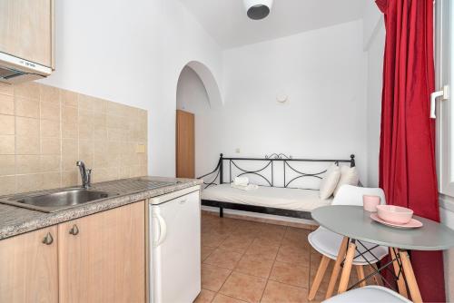a kitchen with a sink and a table with a bed at Ornos Apartments in Ornos