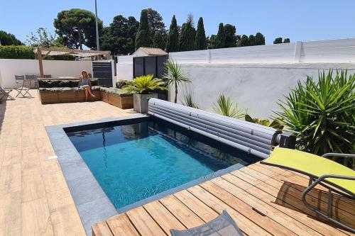a swimming pool on a wooden deck with a yellow chair at Charmante villa proche de la plage (classée 3*) in Pérols