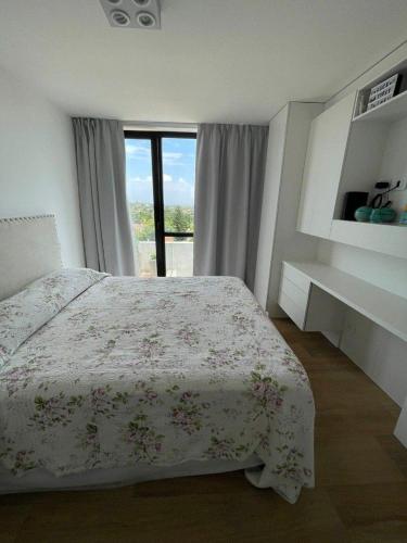 1 dormitorio con 1 cama con colcha de flores y ventana en Anto Dpto Playa Grande en Mar del Plata