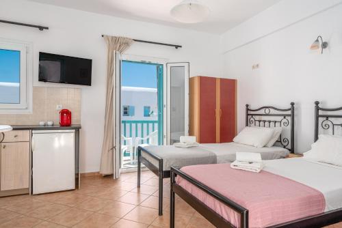 a hotel room with two beds and a balcony at Ornos Apartments in Ornos
