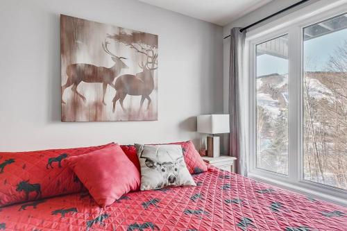 a bedroom with a red bed with a painting on the wall at Le Cozy-Condo à louer à Stoneham (CITQ 239956) in Stoneham