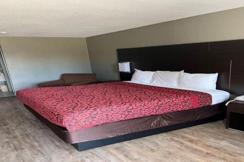 a bed in a hotel room with a red bedspread at Days Inn by Wyndham Tupelo in Tupelo