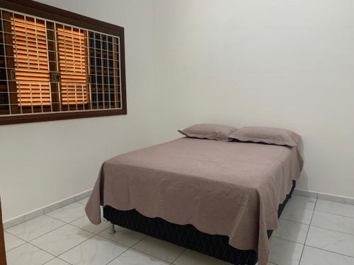a bed in a white room with a window at Casa espaçosa para lazer em família in Águas de São Pedro