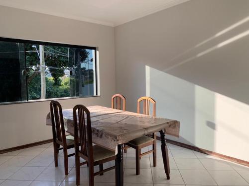 a dining room table with four chairs and a window at Casa espaçosa para lazer em família in Águas de São Pedro