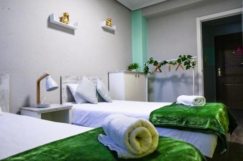 瓦倫西亞的住宿－Bioparco Apartment，一间卧室配有两张带绿色床单和毛巾的床。