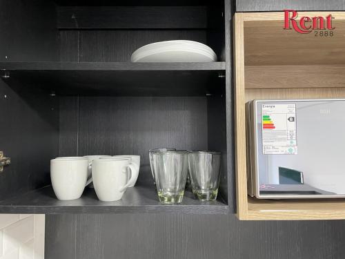a shelf with cups and plates and a microwave at Rent Muñiz in Buenos Aires