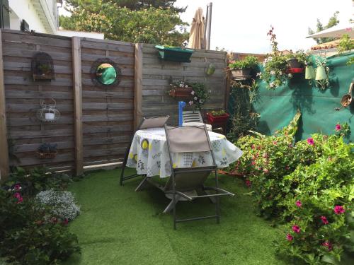 a garden with a table and some flowers and a fence at Appartement à l’étage indépendant in Ars-en-Ré