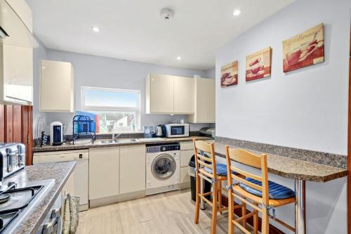 une cuisine avec des placards blancs et un comptoir avec des chaises dans l'établissement Lovely 2 bedroom duplex apartment, Maidstone sleeps 5, à Kent