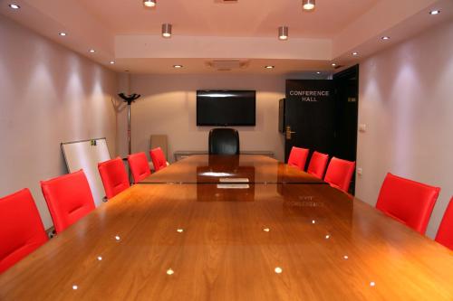 a conference room with a large wooden table and red chairs at Hotel Dolce International in Skopje