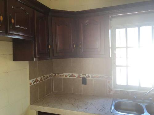 a kitchen with brown cabinets and a sink and a window at The Short STOP free Breakfast private Apartment in Monte Plata