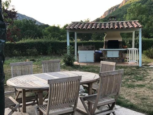 - une table et des chaises en bois avec un grill dans la cour dans l'établissement La maison des Pins, à Saint-Julien-du-Verdon