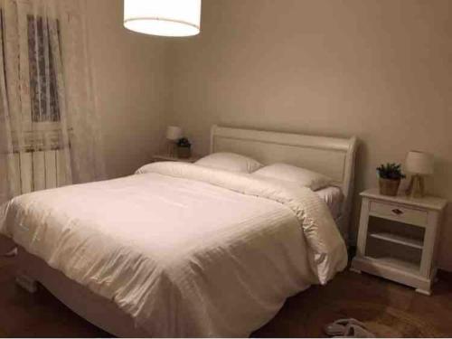 - une chambre avec un lit blanc et une table de nuit dans l'établissement La maison des Pins, à Saint-Julien-du-Verdon