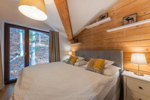1 dormitorio con 1 cama y pared de madera en Lúčnica apartments Tále en Tale