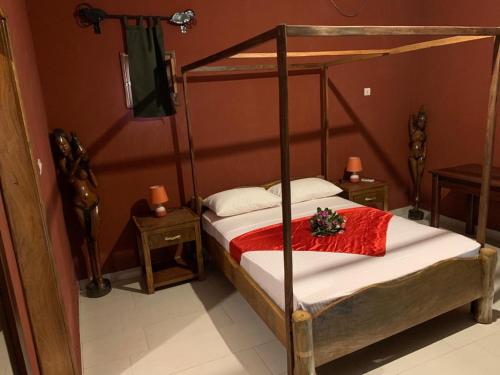 Chez Kangou Lodge في Fimela: غرفة نوم بسرير مع اطار سرير خشبي