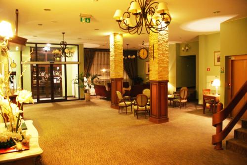 a lobby with a waiting area with chairs and tables at Hotel Wilga by Katowice Airport in Pyrzowice