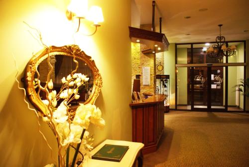a room with a mirror and a table with flowers at Hotel Wilga by Katowice Airport in Pyrzowice