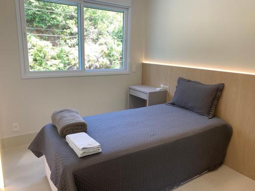 Dormitorio pequeño con cama y ventana en Lindo Apartamento em Jurerê com piscina, en Florianópolis