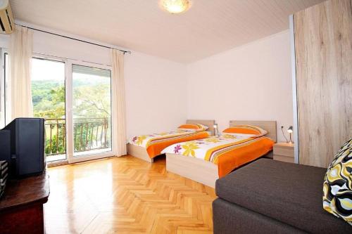 two beds in a room with a tv and a couch at Villa Marietta Equino in Donje Sitno