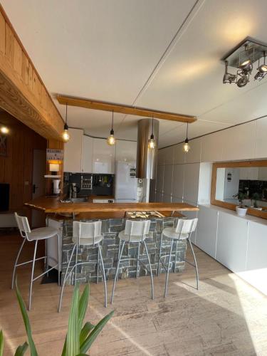 - une cuisine avec un bar avec des tabourets blancs dans l'établissement Agréable appartement de 65m2 vue exceptionnelle, à Font-Romeu-Odeillo-Via