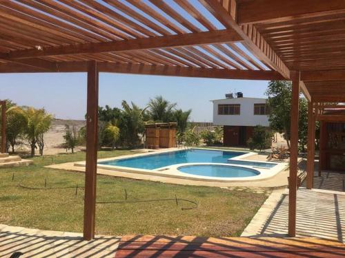 a swimming pool in a yard with a wooden pergola at Kalani heights 1 bedroom house that sleeps 6 in Colán