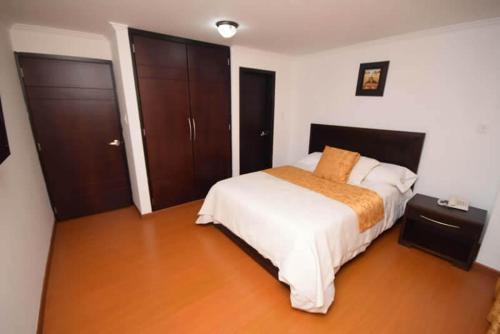a bedroom with a bed with white sheets and an orange blanket at HOTEL ZAFIRO PLAZA in Tunja