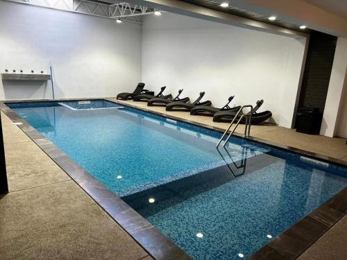 uma piscina com cadeiras pretas num quarto em Madison Suites em Cuauhtémoc