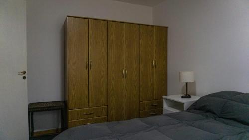 1 dormitorio con un gran armario de madera junto a una cama en Mirando al Olivia en Ushuaia