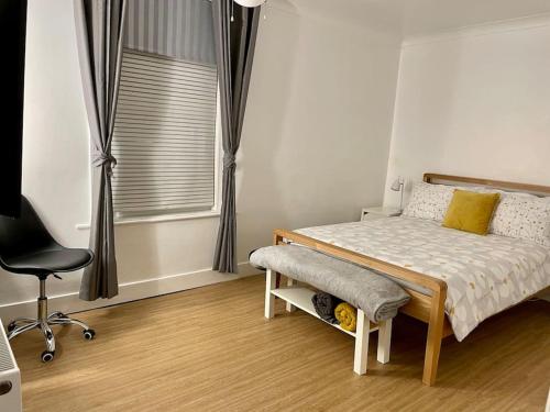 a bedroom with a bed and a chair and a window at Central Worthing, 3 bedrooms, 600m from beach in Broadwater