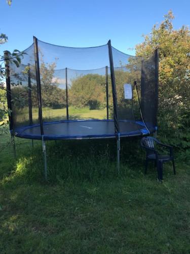 een trampoline met een stoel in het gras bij Bed en Breakfast In het Fruit in Zuidoostbeemster