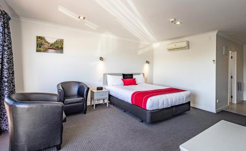 Habitación de hotel con cama y silla en Pukekura Motor Lodge en New Plymouth