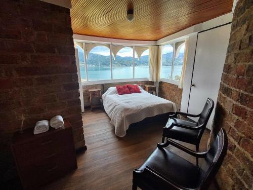 a bedroom with a bed and a chair in front of a window at Refugio Génesis habitaciones Lago de Tota in Tota