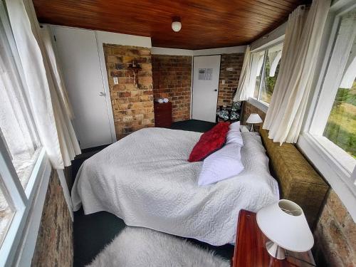 a small bedroom with a bed and a brick wall at Refugio Génesis habitaciones Lago de Tota in Tota