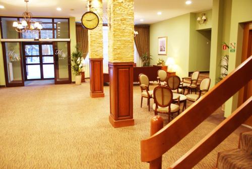 a lobby with a waiting room and a clock on the wall at Hotel Wilga by Katowice Airport in Pyrzowice