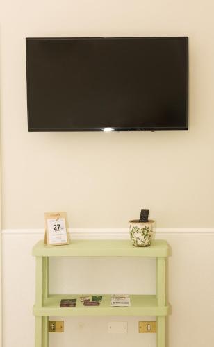 a flat screen tv on a wall with a green table at La Volta in Manduria
