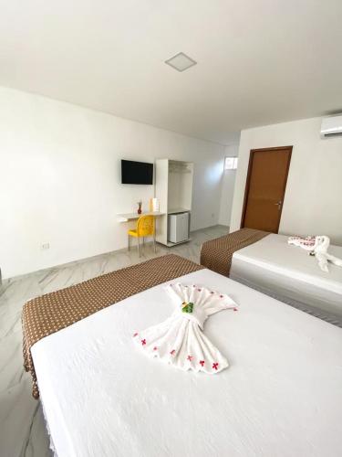 a hotel room with two beds with a flower on it at Pousada O Sol De Maragogi in Maragogi